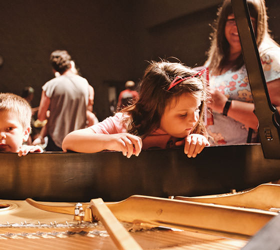 Children looking inside of a piano